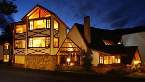 Una casa de varios pisos con fachada de piedra, ventanas grandes y una chimenea.