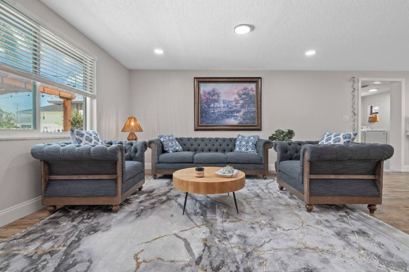 A living room with a marble floor, a large painting on the wall, and a sofa set.