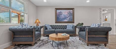 A living room with a marble floor, a large painting on the wall, and a sofa set.