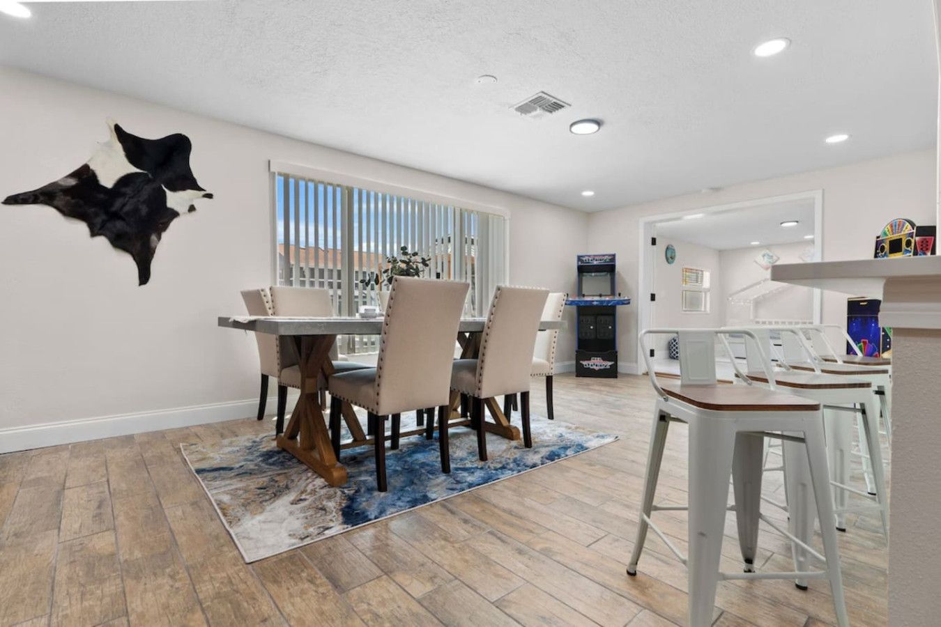 Un coin repas comprenant une table, des chaises, un tapis et une tête d’animal fixée au mur.