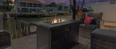 Un patio con una chimenea, muebles de mimbre y vistas a un embarcadero y edificios.