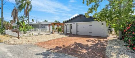 Een woonhuis met een verharde oprit, een garage en een overdekt terras.