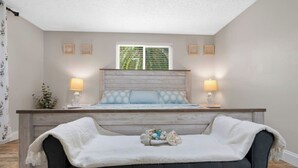 A bedroom with a bed, bedside lamps, a nightstand, a window with blinds, and a decorative tray on the bed. - 4BR Waterfront | Boat Dock + Pool | 11-Min Walk to Beach | Sleeps 8 (Hudson)