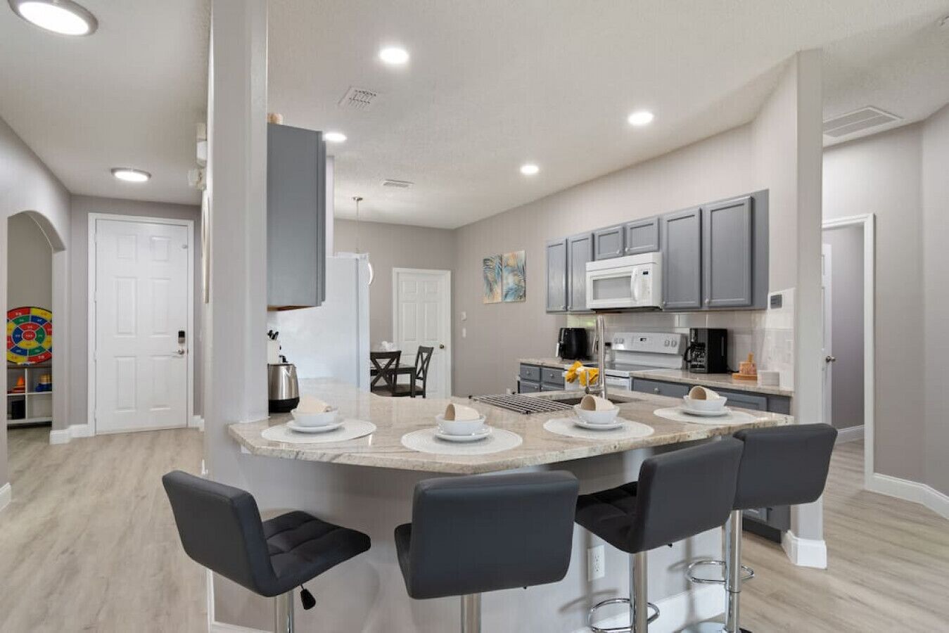 A modern kitchen with a central island, bar stools, and a dining area.