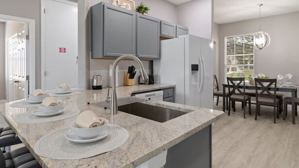Una cocina moderna con gabinetes grises, encimera de granito y lavadero integrado.
