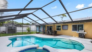 A swimming pool with a sunshade structure, a barbecue area, and a covered patio. - 3BR | Saltwater Pool + Spa | Solar Heated | 9 Min to Airport | Sleeps 7 (Clearwater)
