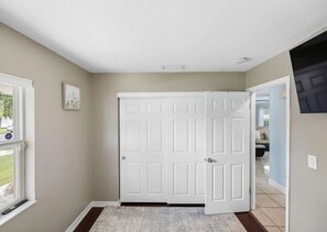 A hallway with a white door, a small rug, and a picture on the wall. - 3BR | Saltwater Pool + Spa | Solar Heated | 9 Min to Airport | Sleeps 7 (Clearwater)