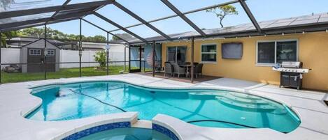 Une piscine dotée d’une structure servant de parasol, d’un espace barbecue et d’un patio couvert.