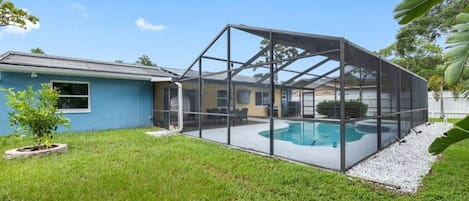 Un patio trasero con piscina, un porche cubierto y una casa.