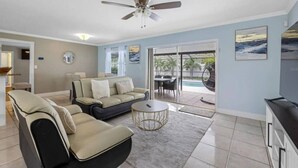 A modern living room with a sofa, coffee table, and ceiling fan. - 3BR | Saltwater Pool + Spa | Solar Heated | 9 Min to Airport | Sleeps 7 (Clearwater)