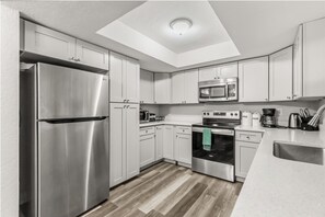 A modern kitchen with stainless steel appliances, white cabinetry, and a skylight. - 4BR | Screened Pool | Next to Park | 10 Min Indian Rocks Beach | Sleeps 10 (Largo)