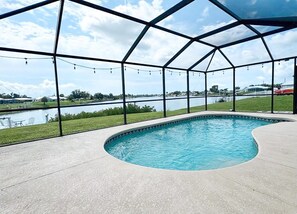 Ein überdachter Pool mit Blick auf einen See und entfernte Gebäude.