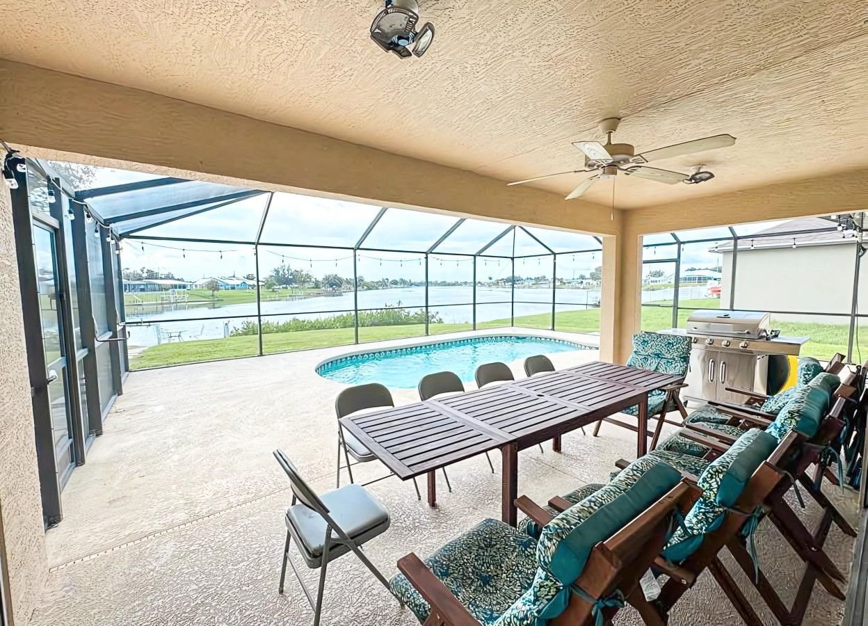 Une terrasse extérieure avec une piscine, un barbecue et une table avec des chaises.