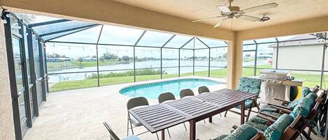 Une terrasse extérieure avec une piscine, un barbecue et une table avec des chaises.