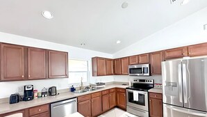 A modern kitchen with wooden cabinets, stainless steel appliances, and a dishwasher. - 3BR Waterfront Views | Pool + BBQ | 3 King Beds | Sleeps 7 | Port Charlotte (Port Charlotte)