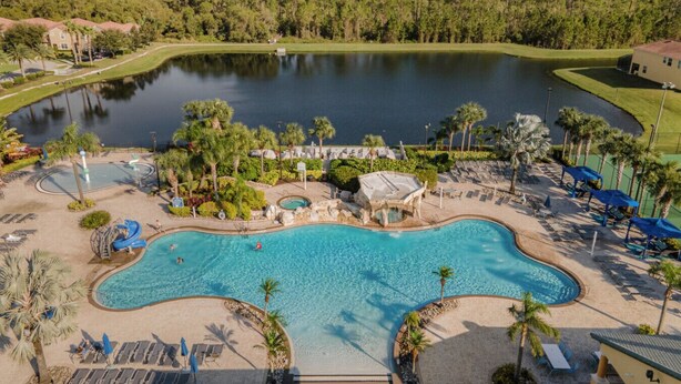 Un resort con una gran piscina, una cascada pequeña y vistas a un lago.