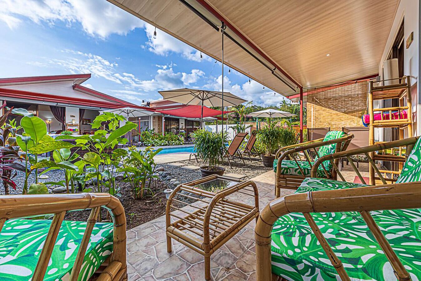 An outdoor patio area with bamboo chairs, a pool, and umbrellas providing shade.