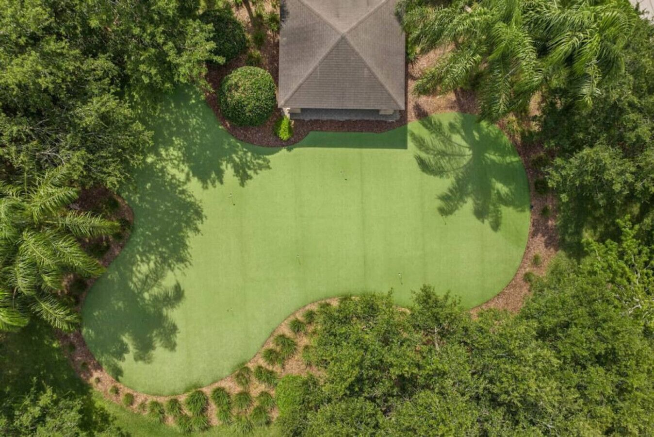 En vy över en golfbana från ovan, med ett hus i mitten, omgivet av tät vegetation.