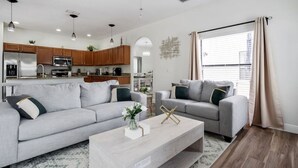 Ein modernes Wohnzimmer mit zwei grauen Sofas, einem Couchtisch und einer Küche im Hintergrund.