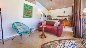 A spacious living area with a red sofa, a teal chair, and a wooden coffee table. A ceiling fan and a painting of a tree are visible. - Villa Colibri, Uvita, 1BR/1BA poolside, near beach (Uvita)