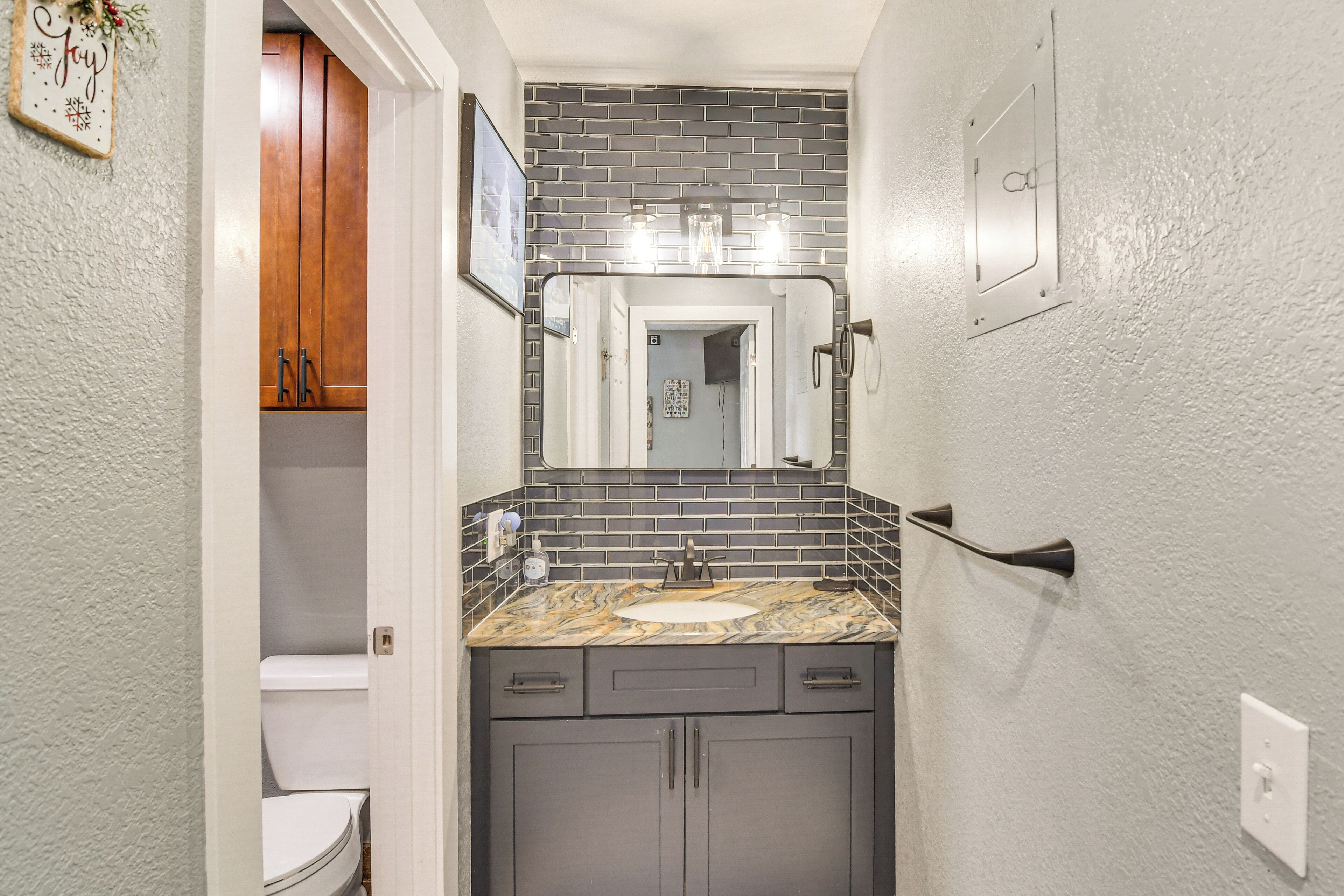 A bathroom with a white toilet, a sink with a marble countertop, and a mirror above the sink.
