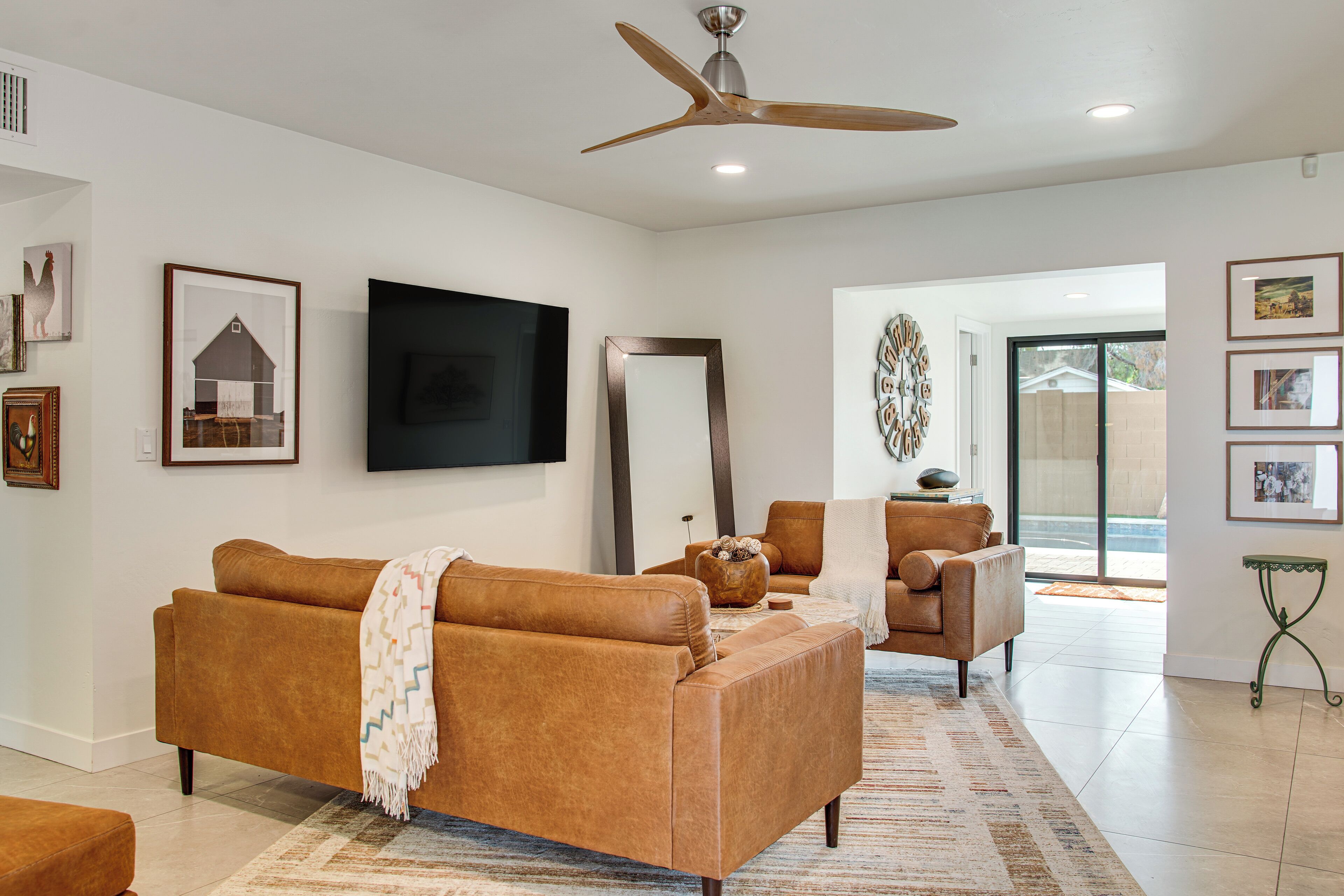 A living room with a brown sofa, a television, and a ceiling fan.