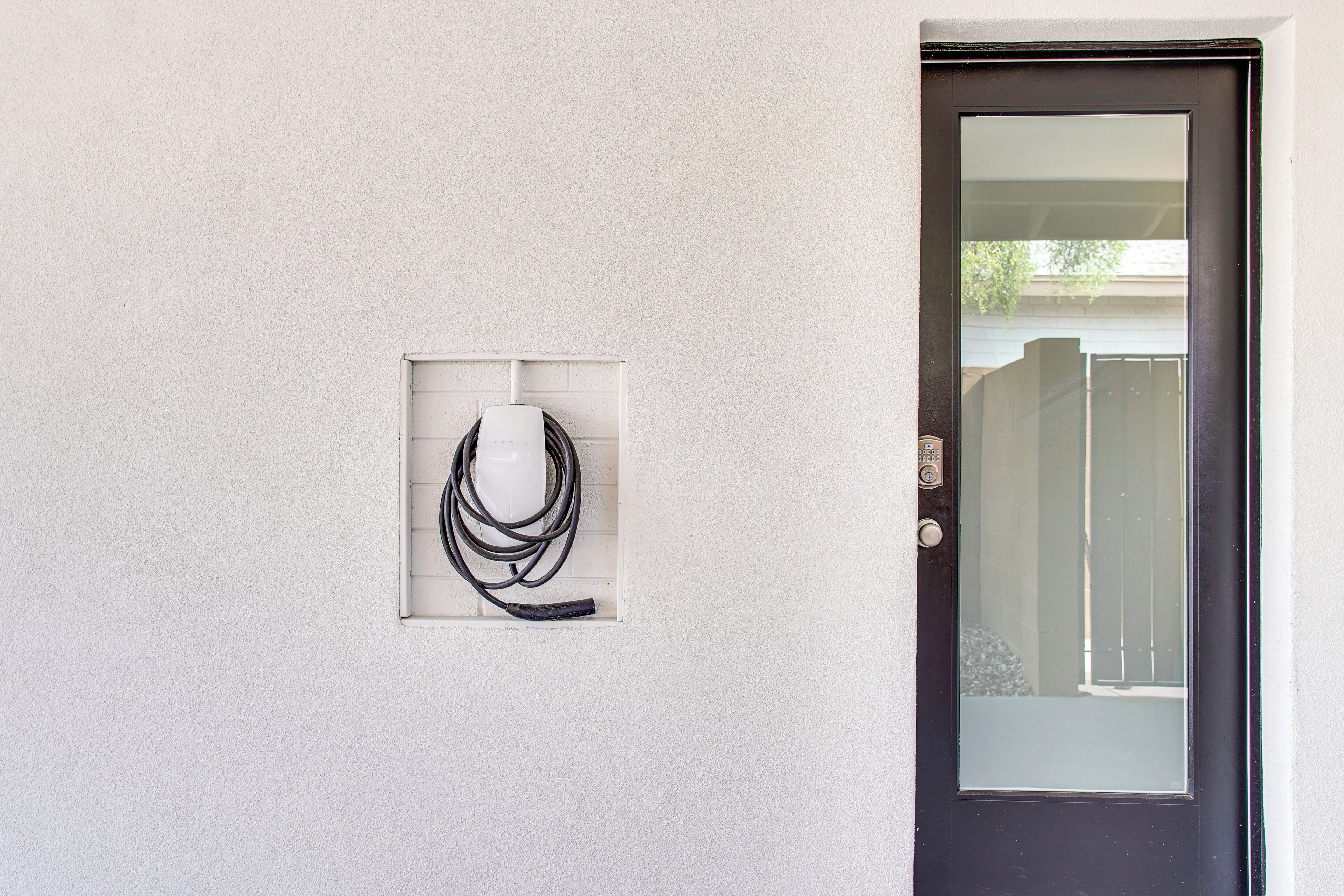 Puerta con panel de vidrio y pared blanca con toma de corriente.
