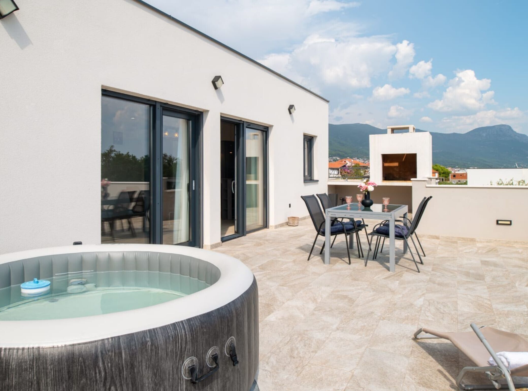 Une terrasse extérieure moderne, dotée d’un jacuzzi, d’un coin repas et offrant une vue sur les montagnes.