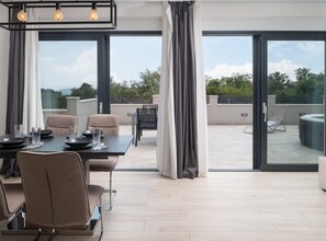 A modern dining area with a table set for four, large windows, and a view of the outdoors.