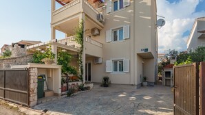 Ein zweistöckiges Wohngebäude mit Balkon, Steinstufen und Blumentöpfen.