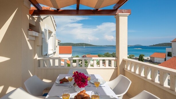 Ein Balkon mit Frühstückstisch und Blick auf die Küste.