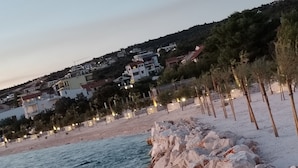 Eine Küstenlandschaft mit felsigem Ufer, einem Strand und Gebäuden im Hintergrund.