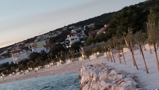 A coastal scene with a rocky shoreline, a beach, and buildings in the background. - Apartment Bella Vista - Two Bedroom Apartment with Terrace (A4) (Sevid)