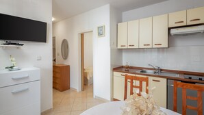 A modern kitchen with white cabinets, a built-in oven, and a dining area with a table and chairs. - Apartment Bella Vista - Two Bedroom Apartment with Terrace (A4) (Sevid)