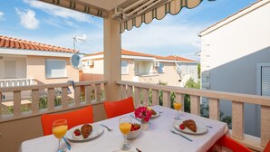 A balcony with a table set for breakfast, including croissants, fruit, and orange juice. - Apartment Bella Vista - Two Bedroom Apartment with Terrace (A4) (Sevid)
