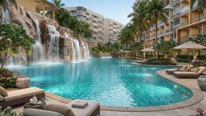 A resort pool with a waterfall, lounge chairs, and palm trees. - Laguna beach resort maldives 3 - Modern studio pool view with balcony in Jomtien (Muang Pattaya)