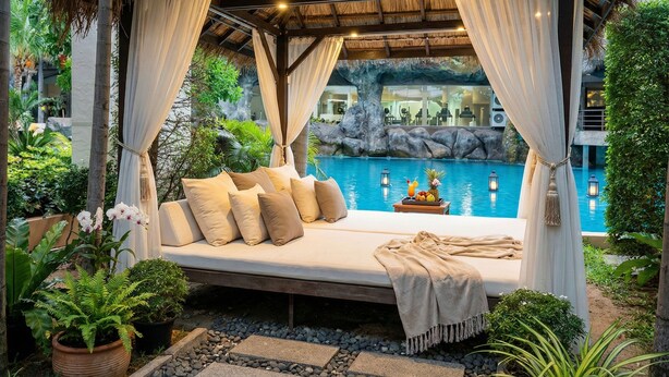 A thatched-roof gazebo with a bed, a pool, and tropical plants. - Laguna beach resort maldives 3 - Modern studio pool view with balcony in Jomtien (Muang Pattaya)