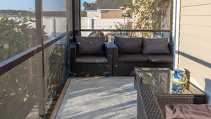 A balcony with wicker furniture, a glass table, and a view of a residential area. - Perfect Stop • Near I-95, Downtown & Civic Center and Darlington (Florence)