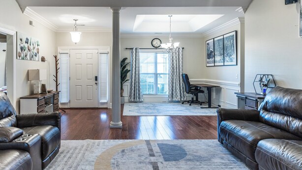 A spacious living room with a large leather sofa, a coffee table, and a rug. There is a dining area with a table and chairs, and a kitchen area with a countertop and appliances. - Perfect Stop • Near I-95, Downtown & Civic Center and Darlington (Florence)
