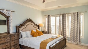 A bedroom with a large bed, wooden headboard, and a ceiling fan. There is a nightstand with a lamp and a dresser with drawers. - Perfect Stop • Near I-95, Downtown & Civic Center and Darlington (Florence)
