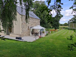 A stone house with a patio, outdoor seating, and a view of a green field.