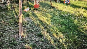 A garden with a stone wall, a swing set, and a target on the ground.