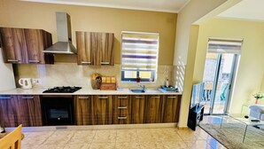Una cocina moderna con armarios de madera, estufa a gas y una ventana con persianas.