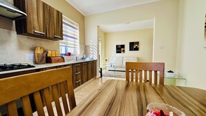 Una cocina moderna con armarios de madera, una mesa de comedor con sillas y una sala de estar con sofá y arte decorativo en la pared.