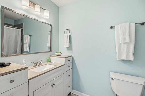 Ein Badezimmer mit Waschbecken, Spiegel, Handtuchhalter und Toilette.