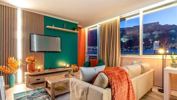 Ein modernes Wohnzimmer mit einer Couch, einem Couchtisch und einem an der Wand befestigten Fernseher.