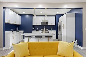 A modern kitchen with white cabinets, a central island, and bar stools.