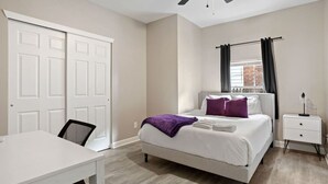 A bedroom with a bed, a desk, a chair, a nightstand, and a ceiling fan. - Chic Design and Modern Comfort - Inviting Boho Escape (Indianapolis)