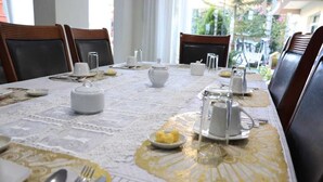 A dining table set with white tableware, including plates, cups, and a teapot, on a lace tablecloth. - hotel florez boutique (Arequipa)
