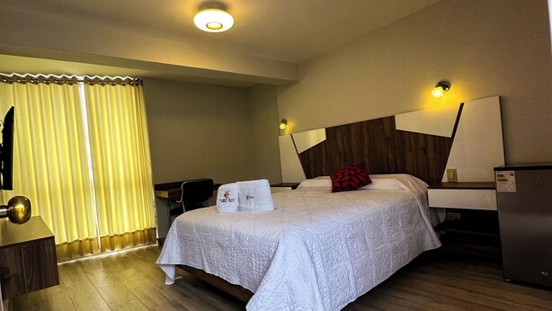 A hotel room with a bed, a desk, a chair, and a wardrobe. - hotel florez boutique (Arequipa)